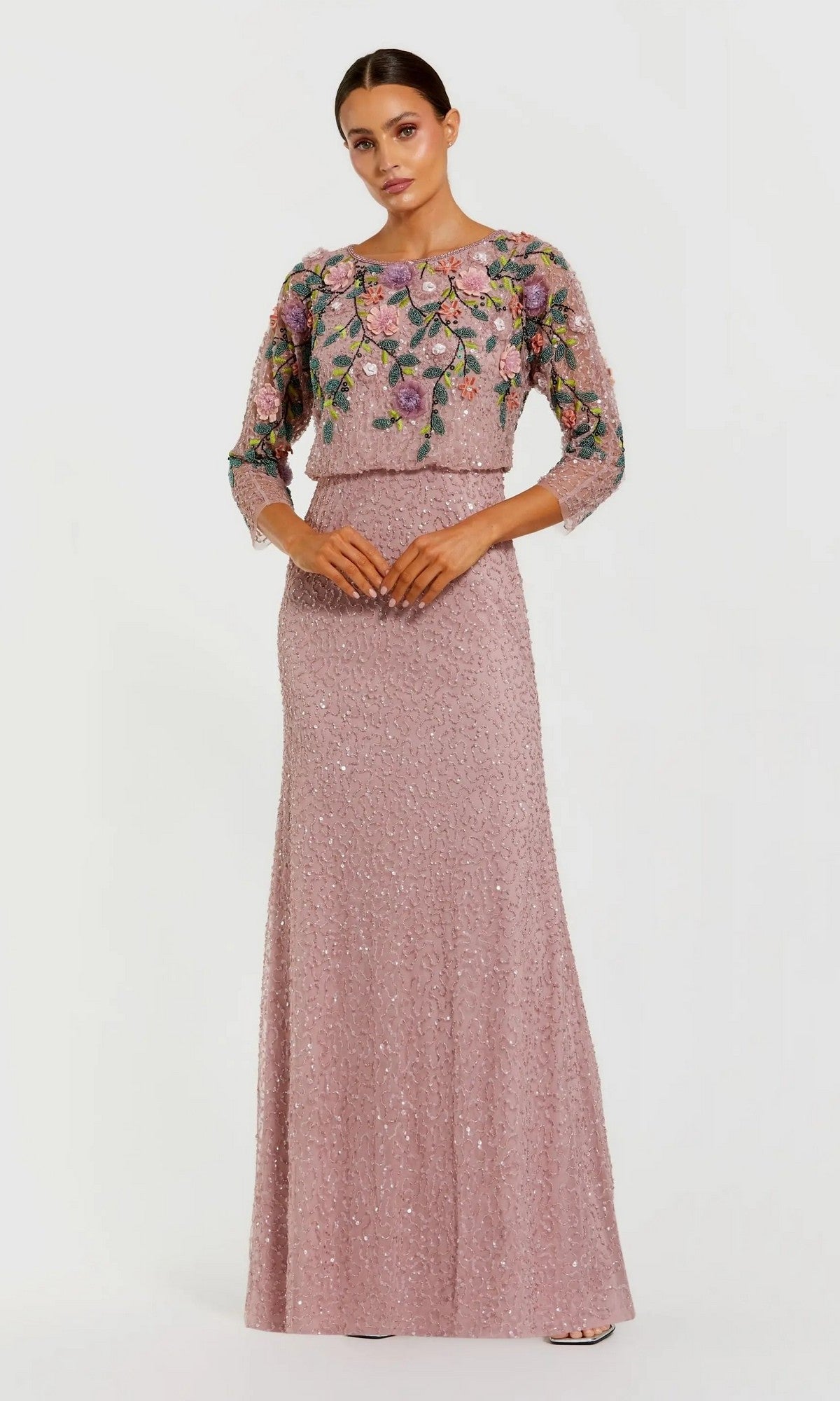 A woman wearing the Mac Duggal 9341 Long Formal Dress in Vintage Lilac Multi, a floor-length gown featuring sequin embellishments and a sheer, floral-embroidered top, stands against a plain white background.